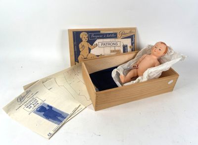 une petite poupée dans une boîte en bois sur laquelle est collée une étiquette