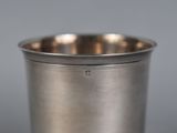 a close up of a silver cup on a gray surface