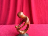 a wooden sculpture of a man sitting on top of a rock