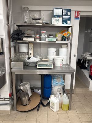 une cuisine avec des étagères en inox et beaucoup de vaisselle sur le plan de travail