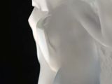 a white vase with a white flower in it on a table