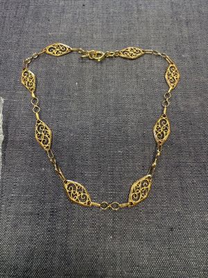 un collier plaqué or posé sur un morceau de tissu