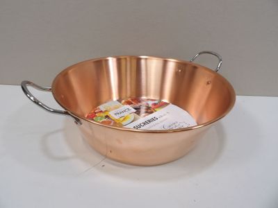 a large copper pan with a handle and a spoon
