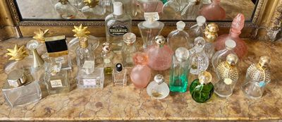 many bottles of perfume sitting on a counter in front of a mirror
