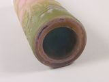 a green vase with a brown handle on a white surface