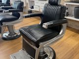 black and chrome barber chair in front of a stone wall