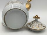 a white and gold teapot with a lid next to it