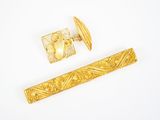 deux bijoux en or posés sur une surface blanche, sur fond blanc