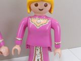 two figurines of a couple dressed in pink and gold