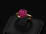 a gold ring with a heart shaped ruby stone in the center