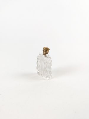 une petite bouteille en verre avec un bouchon doré sur fond blanc
