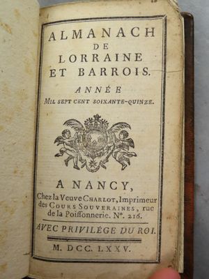 Quelqu'un tient à la main un livre sur lequel figure une image représentant des armoiries.
