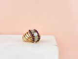 an image of a gold ring with rubies on top of a marble block