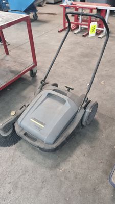 two lawn mowers sitting on the floor in a garage
