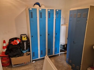 two blue lockers in the corner of a room next to a toilet