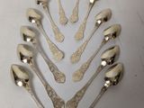 six silver spoons are arranged in a circle on a white surface