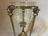 a silver vase with two birds on it on a stand