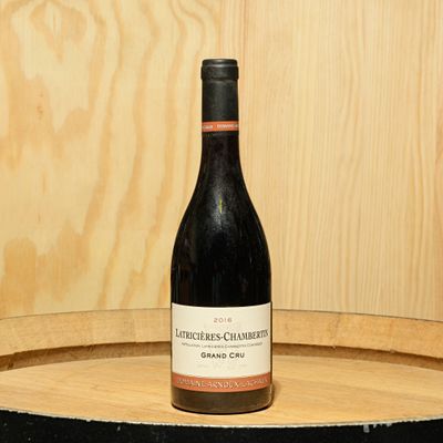 a bottle of wine sitting on top of a wooden barrel