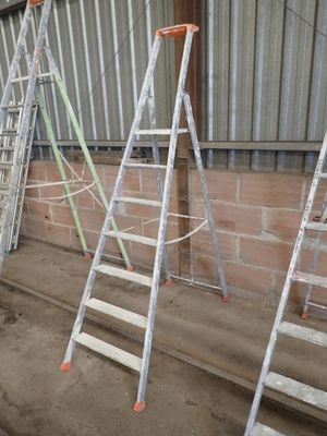 several ladders leaning up against a brick wall in a warehouse