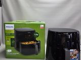 une boîte de nourriture posée sur une table à côté d'une friteuse à air chaud noire