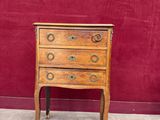 une petite commode en bois exposée devant un mur rouge