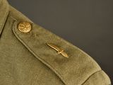 a close up of a military uniform with a gold pin on it