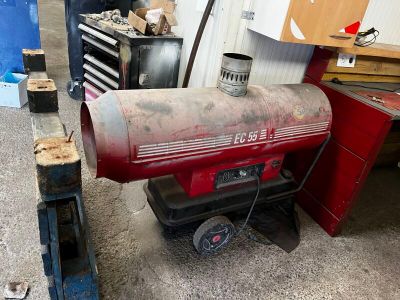 un vieux radiateur à gaz rouge qui traîne dans un garage