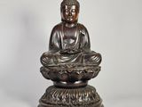 une statue en bronze représentant un Bouddha assis sur une fleur de lotus