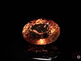 a close up of an orange diamond on a black surface