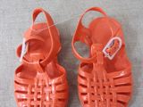 pair of orange sandals with buckles on them sitting on a gray surface
