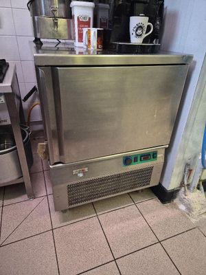 un réfrigérateur en acier inoxydable dans une cuisine, sur lequel est posée une cafetière
