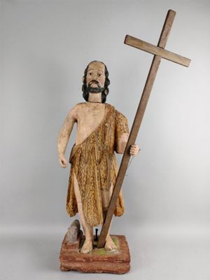 wooden statue of a man holding a cross and a wooden pole