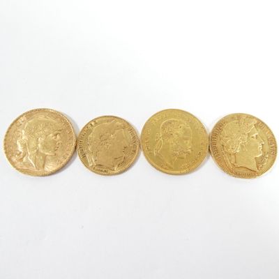 quatre pièces d'or sont alignées sur une surface blanche