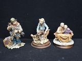 three figurines of a man and a woman sitting on a bench