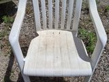 a white plastic chair that is sitting in the dirt