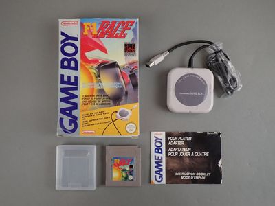 a gameboy next to a game box and a charger