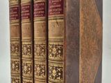 trois vieux livres posés l'un sur l'autre sur une surface blanche