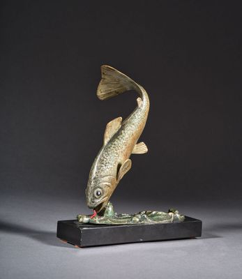 une sculpture représentant un poisson posée sur un socle en bois, avec un fond noir