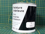 un pot de peinture posé sur un tapis de découpe, à côté d'une règle