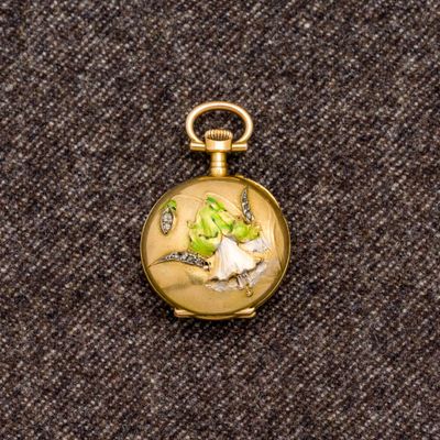 une petite montre de poche en or ornée d'un oiseau