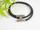 a black leather bracelet with two silver bars on a white surface