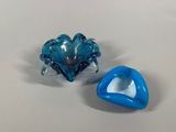 two pieces of blue glass sitting on a white surface