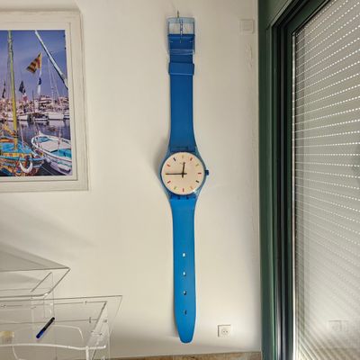 une montre bleue accrochée au mur près d'une fenêtre