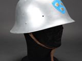 silver steel helmet with blue emblem on it on a black mannequin head