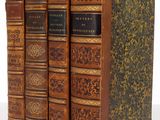 trois livres sont empilés sur une surface blanche