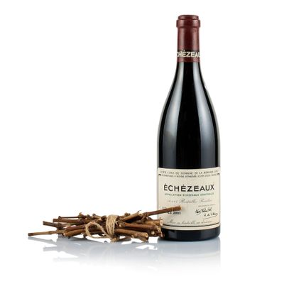 a bottle of red wine sitting next to a bunch of sticks