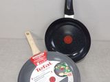 two frying pans and a frying pan sitting on a counter