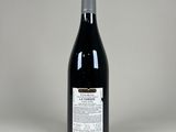 the bottle of red wine is sitting on a white surface