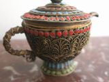 a small metal teapot with a lid on a table