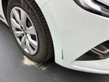 the front end of a white car with a flat tire